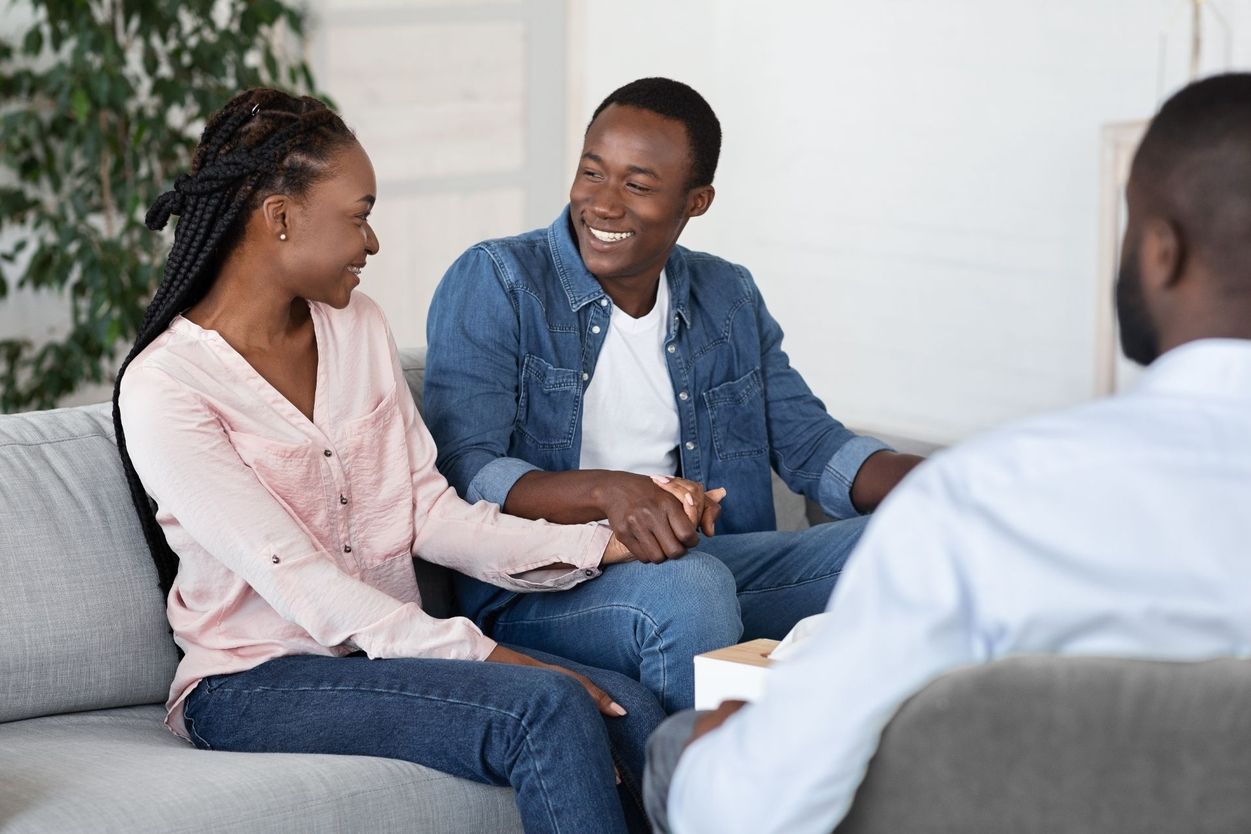 Lächelndes Paar in Beratungsgespräch mit Therapeut auf dem Sofa - symbolisiert Vertrauen Kommunikation und Unterstützung in der Paartherapie oder psychologischen Betreuung