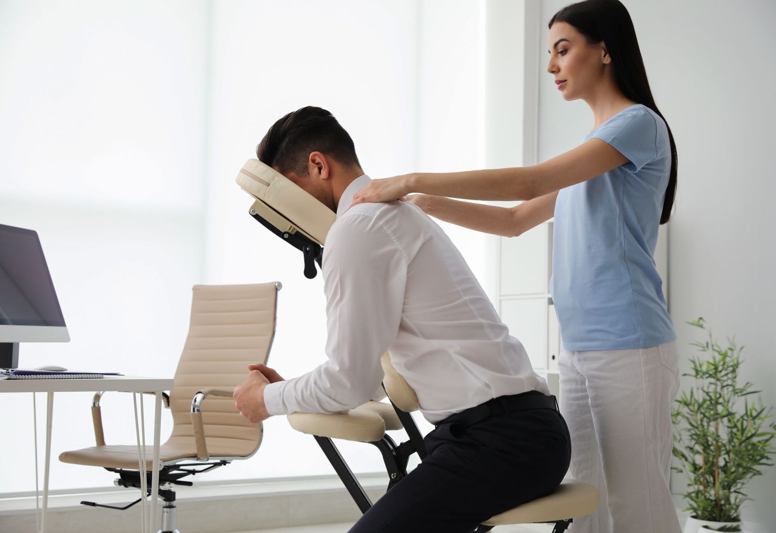 Büroangestellter erhält Nackenmassage auf einem Massagestuhl